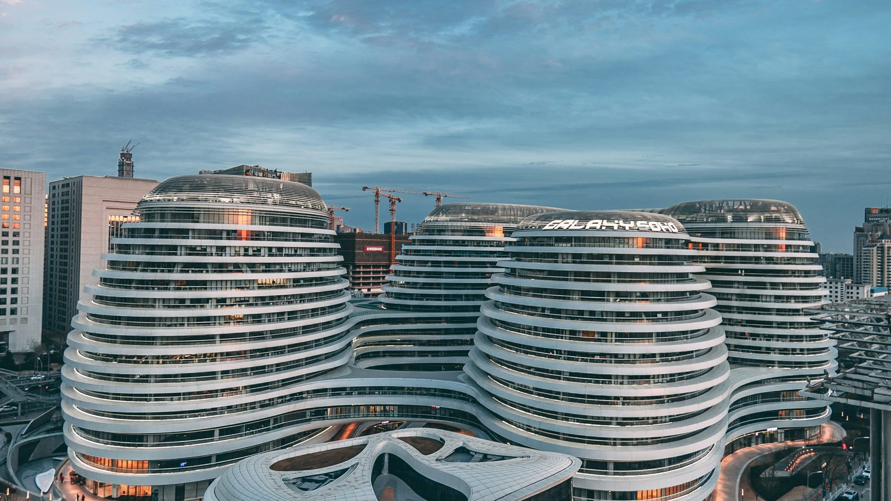 暮色中的北京银河 SOHO，四座白色流线型建筑层层环绕，连廊在楼体之间穿行